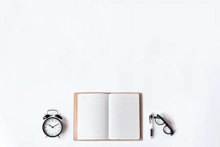 White office desk table with open diary, pen and alarm clock, Top view with copy space, flat lay.の写真素材