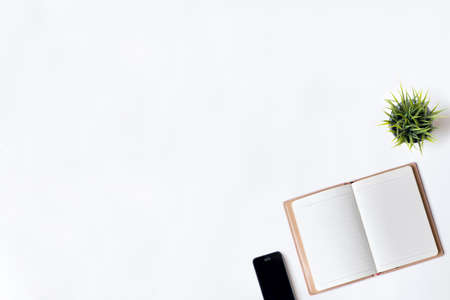 White office desk table with open diary and plant.の写真素材