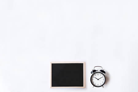 White office desk table with chalkboards and alarm clock. Top view with copy space, flat lay.