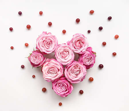 Heart symbol made of bright roses, berries and leaves on white background. Flat layの写真素材