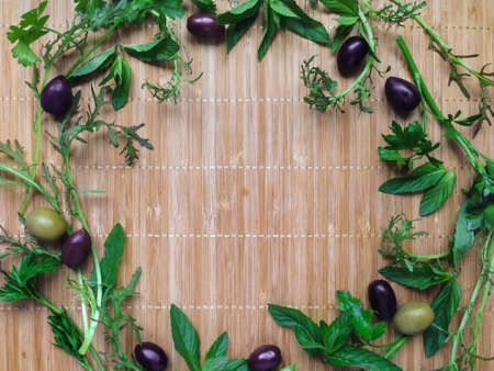 Herbs, olives and spices in a round frame on bamboo background. Top view, flat layの写真素材
