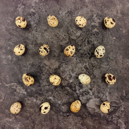 Decorative bright pattern with quail eggs on dark stone background. Flat lay, top view, natural still lifeの写真素材