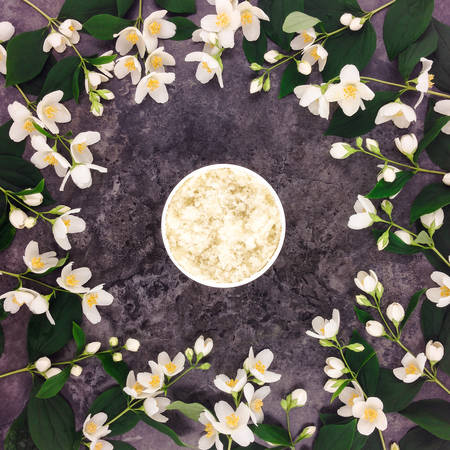 Natural scrub for spa treatment and jasmine flowers on stone background. Flat lay, top view, decorative still lifeの写真素材