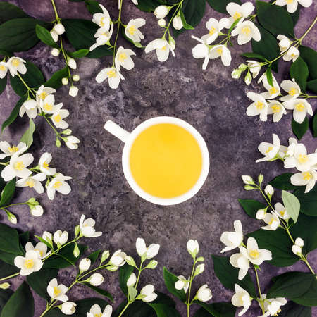 Tea cup with green tea and fresh jasmine flowers on dark stone background. Top view composition, flat lay, view from aboveの写真素材