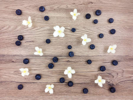 Summer pattern of jasmine flowers and ripe blueberries on wooden table. Flat lay, top viewの写真素材