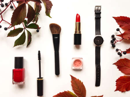 Decorative flat lay composition with cosmetics, woman accessories, decorated with autumn leaves and berries. Flat lay, top view on white background, fashion still-lifeの写真素材