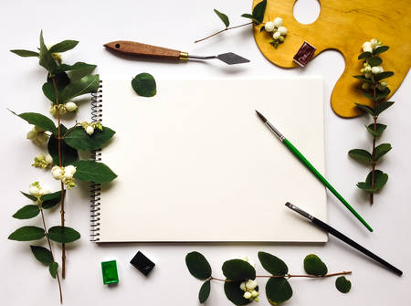 Autumn composition with album, watercolors and brushes on white background, decorated with green...