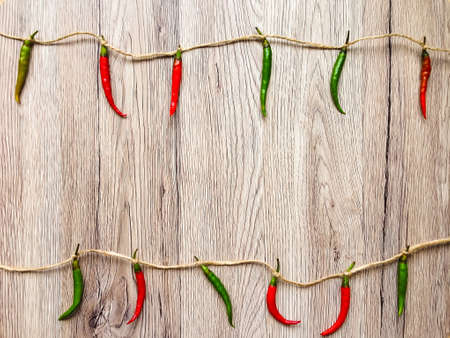 Bright background with red and green chili peppers hanging on twine. Flat lay, top view, view from above, wooden backgroundの写真素材