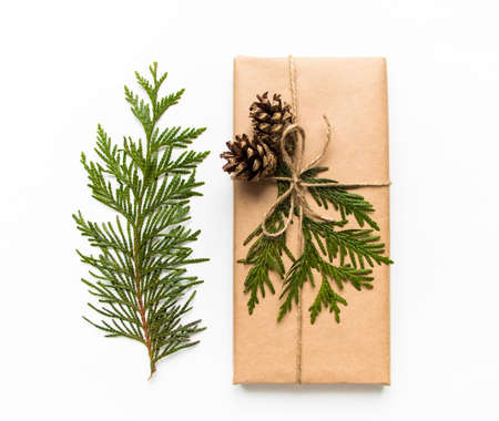 Vintage gift box in craft paper on white background. Present decorated with natural parts. Christmas or other holiday concept, top view, flat layの写真素材