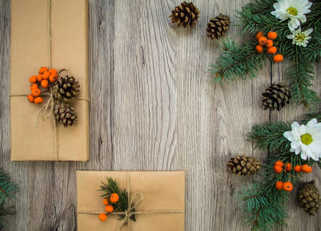 Christmas presents wrapped in kraft paper with natural decoration, berries and flowers. Rustic wooden background from above. Flat lay, top viewの写真素材