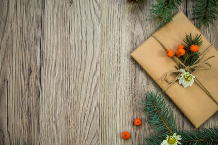Christmas present wrapped in kraft paper with natural decoration, berries and flowers. Rustic wooden background from above. Flat lay, top viewの写真素材