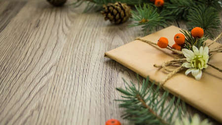 Christmas presents wrapped in kraft paper with natural decoration, berries and flowers. Rustic wooden background from above. Angle viewの写真素材