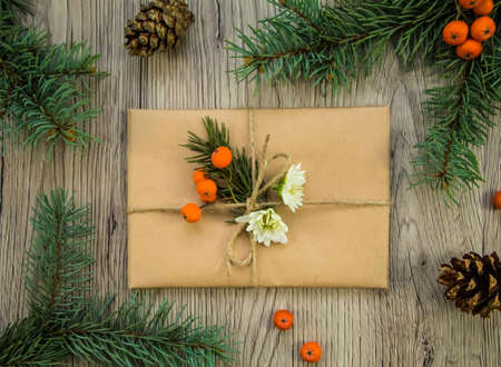 Christmas presents wrapped in kraft paper with natural decoration, berries and flowers. Rustic wooden background from above. Flat lay, top viewの写真素材