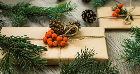 Christmas presents wrapped in kraft paper with natural decoration and berries. Rustic wooden...