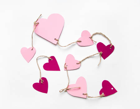 Bright pink paper hearts connected with a rope. Cute handmade cards for Valentine's day. Flat lay on white background, top viewの写真素材