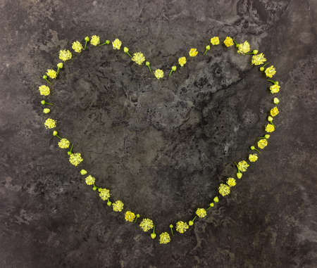 Heart symbol made of small linden flowers on dark marble stone background. Valentine's day composition. Flat lay, top viewの写真素材