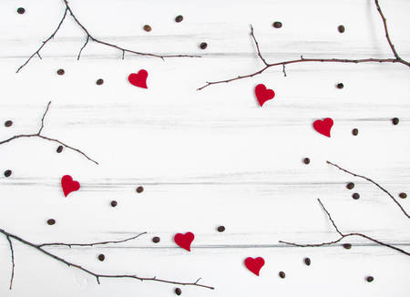 Minimalistic frame with tree branches, woolen hearts and coffee beans on white vintage wooden table. Flat lay, top view with a copy space for your textの写真素材