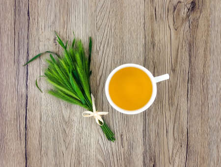 Cute bouquet of spikelets and cup of herbal tea on wooden table. Summer cozy composition, rustic holiday concept. Flat lay, top viewの写真素材