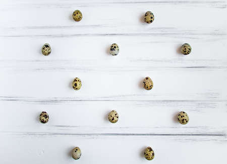 Decorative light pattern with quail eggs on white wooden vintage table. Flat lay, top view, natural still life, eggs polka dotの写真素材