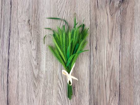 Cute bouquet of spikelets with a cute bow on wooden table with copy space. Summer cozy composition, rustic holiday concept. Flat lay, top view, space for textの写真素材