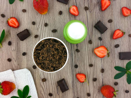 Set of spa treatment products: creme, scrub, decorated with coffee, chocolate and strawberries on wooden table. Home body care concept. Flat lay, top view, overhead viewの写真素材
