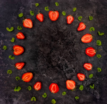 Decorative round frame with fresh strawberries and green leaves. Space for your text. Bright summer ornament. Flat lay, top viewの写真素材