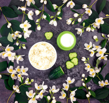 Set of spa treatment products: creme, scrub, decorated with jasmine flowers on dark stone background. Body care concept. Flat lay, top view, overhead viewの写真素材