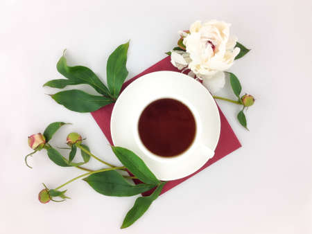 Still life with cup of black coffee, paper napkin and peony flowers on white table. Flat lay, top viewの写真素材