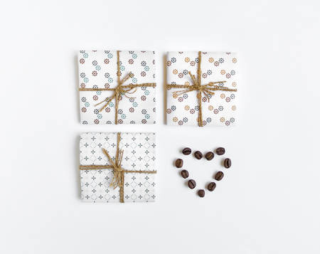 Shot of handmade gift boxes decorated with coffee beans heart on white background. Rustic style, cute paper DIY decoration. Valentine's day or other holiday concept. Flat lay, top viewの写真素材