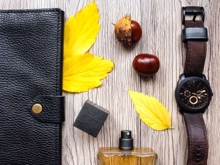Closeup of men's accessories and essential items on wooden background. Decorated with autumn yellow leaves and chestnuts. Flat lay, top view, view from aboveの写真素材