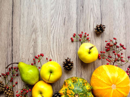 Stylish composition of colorful pumpkins, autumn fruits, cones and berries. Top view on wooden background, bottom composition frame. Autumn flat layの写真素材
