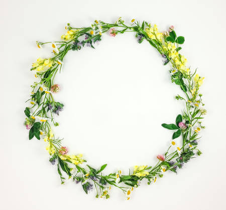 Colorful bright round frame made of summer meadow flowers on white background. Flay lay, top view with copy spaceの写真素材