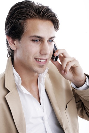Close-up portrait of a young sophisticated businessman talking on a mobile phone on a white background looking at the cameraの写真素材