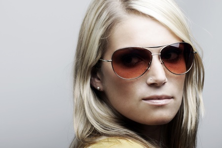Profile portrait of a beautiful Caucasian female model posing in sunglasses, isolated on white background.の写真素材