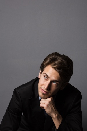 Studio shot of a good looking male model posing as a cool businessman, isolated on gray.の写真素材