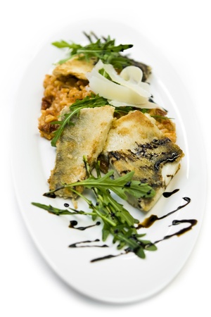 Fried fish and fresh rocket drizzled with sauce served on an oval white platter for a delicious healthy mealの写真素材