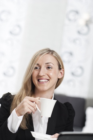 Beautiful businesswoman taking a coffee break smiling happily and enjoying a cup of hot espresso with copyspace aboveの写真素材