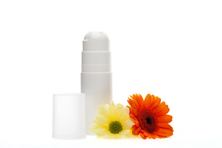 Beauty essentials with two unlabelled white containers for skincare products alongside two colourful fresh Gerbera daisies on a white backgroundの写真素材