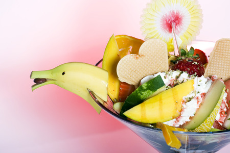 Tropical fruit salad and ice cream garnished with a decorative banana cut to resemble a birds head...