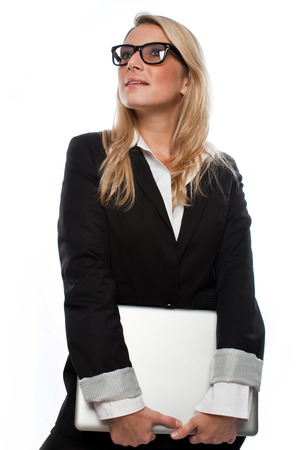 Pretty Blond Businesswoman Wearing Black Business Suit Looking Up While Holding her Laptop. Isolated on White Background.の写真素材