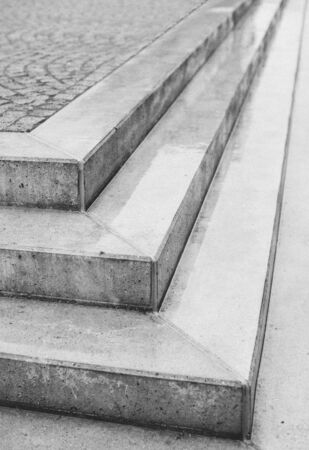 Corner angle of three exterior concrete urban steps with cobblestones above in a street or courtyard with the point of the corner facing the camera in an architectural backgroundの写真素材