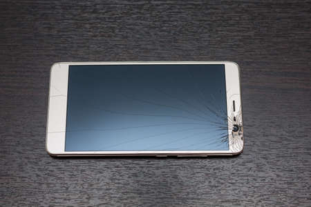 Modern mobile smartphone with broken screen. Cracks on the smartphone glass.