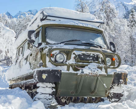 A snow-covered tracked SUV in the mountains in winter. Front view.の写真素材
