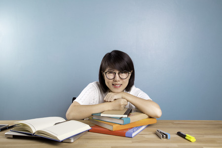 Portrait of clever  asian student with open book reading it  in library