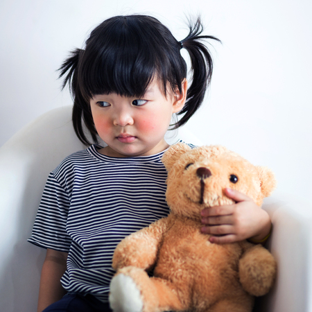 Lovely and innocent asian kid  with teddy looking at somethingの写真素材