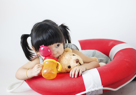 Portrait of lovely little girl with teddy milk bottle and life ringの写真素材