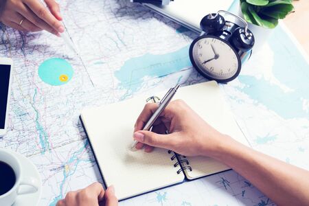 Writing note and consulting for traveling on map at officeの写真素材