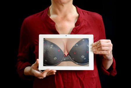 A red dress wearing woman holding a mobile tablet. Showing woman breast.の写真素材
