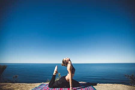 A young woman doing yoga near the ocean at sunrise. This image was taken on January 2013, at Miami...