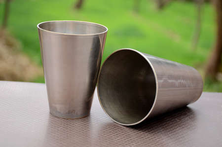 the pair of brown silver color old bronze tumbler on the brown green background.の写真素材